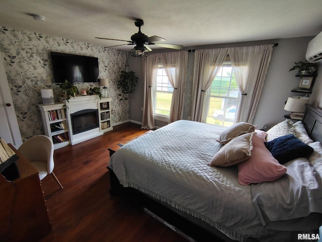 1469 2100th St, Lincoln, IL 62656 - bedroom featuring wood finished floors, wallpapered walls, a glass covered fireplace, ceiling fan, and a wall mounted AC