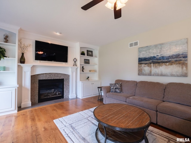 11014 N Saddlehorn Way, Dunlap, IL 61525 - living area featuring light wood-style flooring, a ceiling fan, a fireplace, and built in features