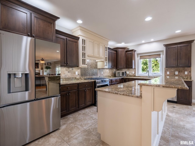 11014 N Saddlehorn Way, Dunlap, IL 61525 - kitchen with stainless steel appliances, dark brown cabinetry, stone counters, tasteful backsplash, and a kitchen island