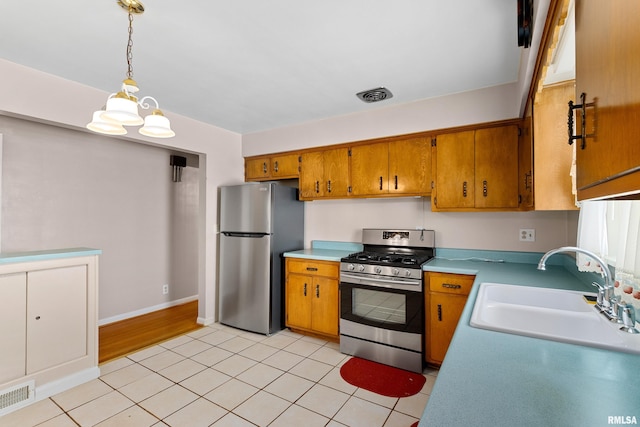 2400 W Callender Ave, West Peoria, IL 61610 - kitchen with stainless steel appliances, light countertops, brown cabinets, decorative light fixtures, and light tile patterned floors