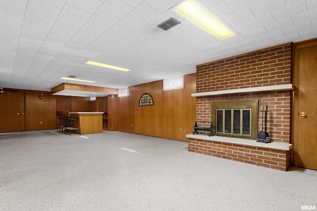 2400 W Callender Ave, West Peoria, IL 61610 - unfurnished living room featuring wooden walls, bar, and a brick fireplace
