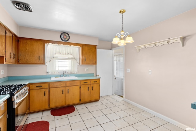 2400 W Callender Ave, West Peoria, IL 61610 - kitchen with stainless steel gas range, a chandelier, light countertops, brown cabinetry, and hanging light fixtures