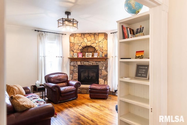 306 W Fremont St, Elmwood, IL 61529 - living room featuring a stone fireplace, wood finished floors, built in shelves, and crown molding