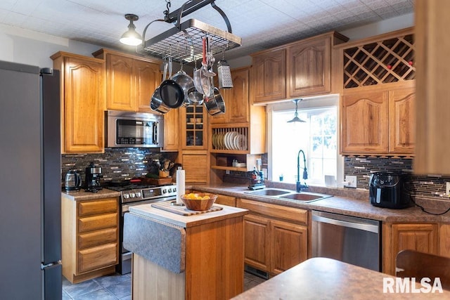 306 W Fremont St, Elmwood, IL 61529 - kitchen featuring appliances with stainless steel finishes, backsplash, a center island, light tile patterned flooring, and brown cabinetry