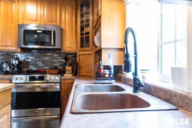 306 W Fremont St, Elmwood, IL 61529 - kitchen featuring stainless steel appliances, decorative backsplash, light countertops, and brown cabinetry