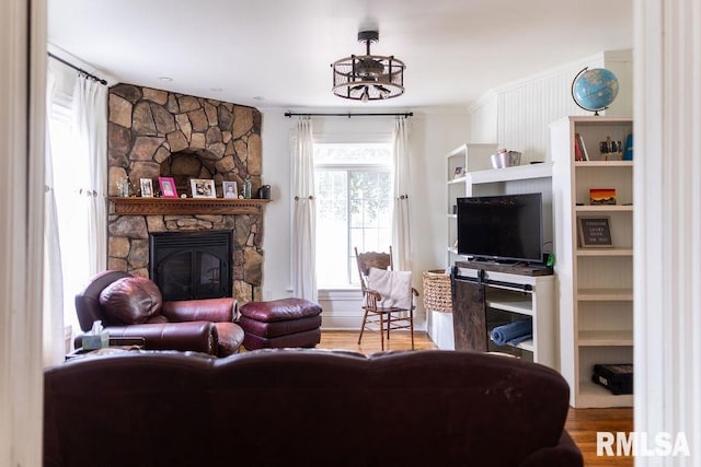 306 W Fremont St, Elmwood, IL 61529 - living room featuring wood finished floors, a stone fireplace, and crown molding
