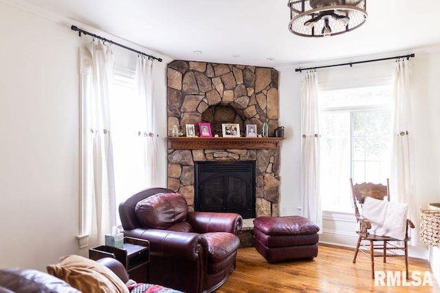 306 W Fremont St, Elmwood, IL 61529 - living room featuring wood finished floors, crown molding, a stone fireplace, and a chandelier