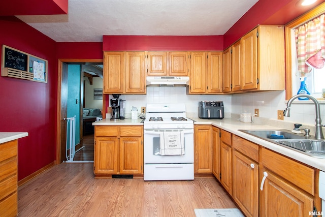 1926 W Callender Ave, West Peoria, IL 61604 - kitchen with white range with gas cooktop, under cabinet range hood, light countertops, and light wood-type flooring