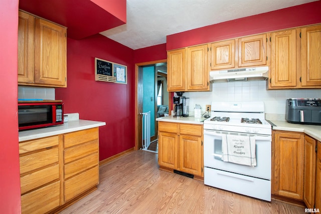 1926 W Callender Ave, West Peoria, IL 61604 - kitchen featuring white range with gas cooktop, under cabinet range hood, light countertops, and light wood finished floors