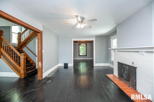 1121 N University St, Peoria, IL 61606 - unfurnished living room with stairway, wood finished floors, ceiling fan, and a brick fireplace