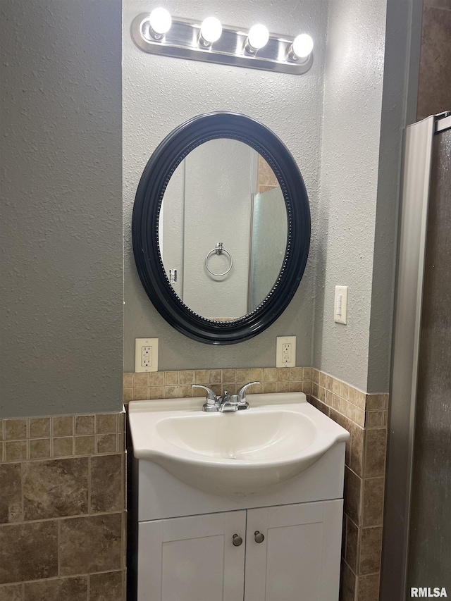 236 W Grant St, Macomb, IL 61455 - bathroom with tile walls, vanity, a textured wall, and a wainscoted wall