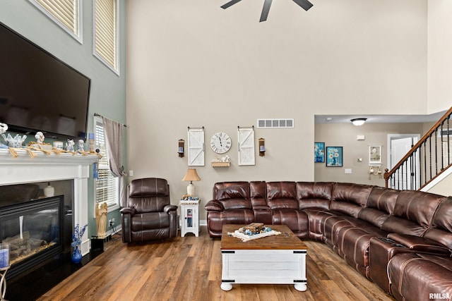 824 Debates St, Washington, IL 61571 - living area with a towering ceiling, ceiling fan, wood finished floors, a glass covered fireplace, and stairs