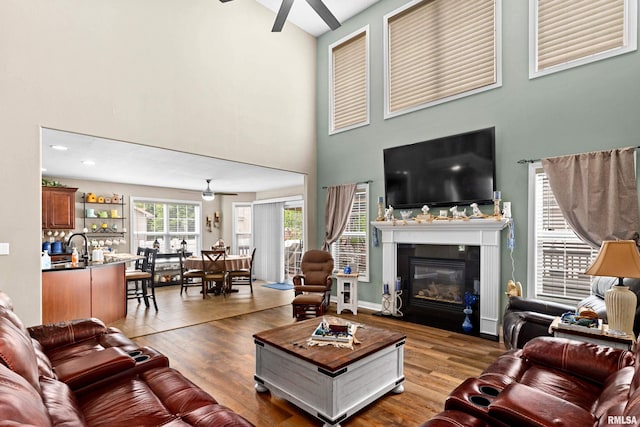 824 Debates St, Washington, IL 61571 - living area featuring a ceiling fan, a towering ceiling, wood finished floors, and a fireplace with flush hearth