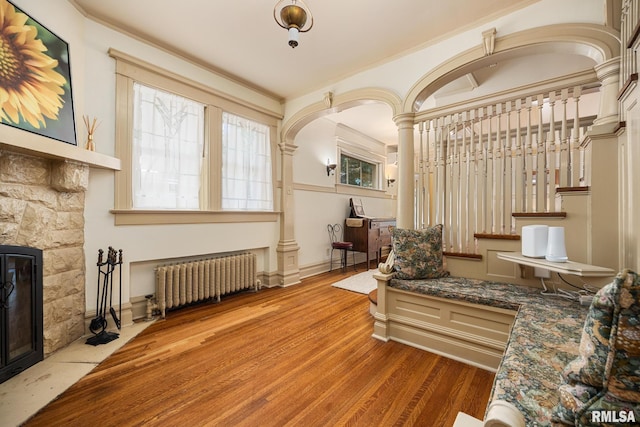 1227 W Barker Ave, Peoria, IL 61606 - living area with radiator, a fireplace, wood finished floors, ornate columns, and stairs
