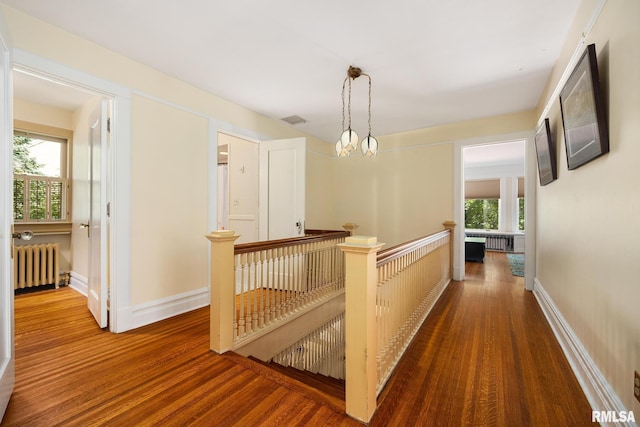 1227 W Barker Ave, Peoria, IL 61606 - hallway featuring radiator, wood finished floors, an upstairs landing, and a chandelier