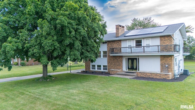 2810 Deveron Cir, Pekin, IL 61554 - rear view of house featuring a balcony, solar panels, a chimney, brick siding, and a lawn
