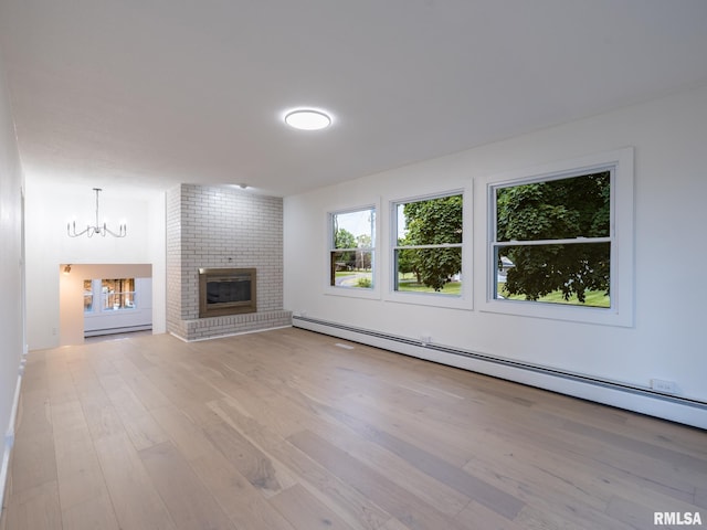 2810 Deveron Cir, Pekin, IL 61554 - unfurnished living room featuring a baseboard heating unit, a chandelier, wood finished floors, and a brick fireplace