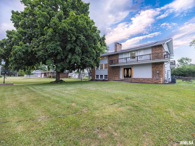2810 Deveron Cir, Pekin, IL 61554 - rear view of property featuring a balcony, brick siding, a lawn, and a chimney