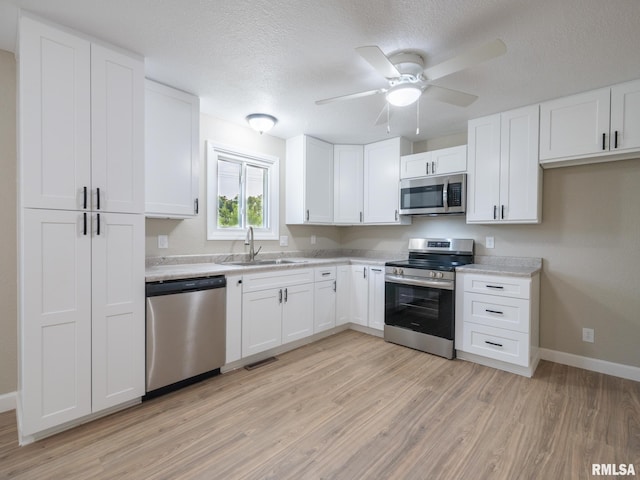 2922 W Larchmont Ln, Peoria, IL 61615 - kitchen featuring stainless steel appliances, light wood finished floors, light countertops, white cabinetry, and a textured ceiling