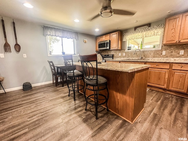 8373 State Route 93rd Rd, Toulon, IL 61483 - kitchen featuring a kitchen bar, stainless steel microwave, range with electric stovetop, ceiling fan, and backsplash