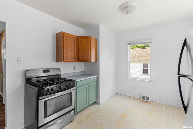 2046 W Wilson Ave, Peoria, IL 61604 - kitchen featuring stainless steel gas stove, light floors, light countertops, refrigerator, and green cabinetry