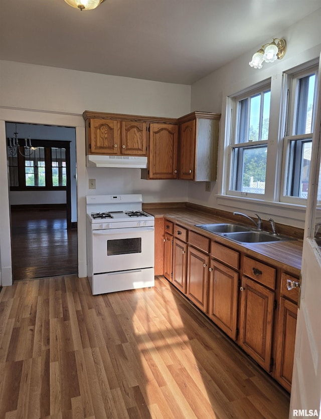 1113 S 5th St, Pekin, IL 61554 - kitchen featuring white gas stove, under cabinet range hood, healthy amount of natural light, and brown cabinets