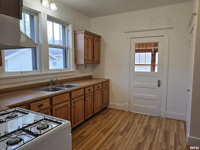 1113 S 5th St, Pekin, IL 61554 - kitchen with white gas range oven, range hood, light wood-style flooring, and brown cabinetry