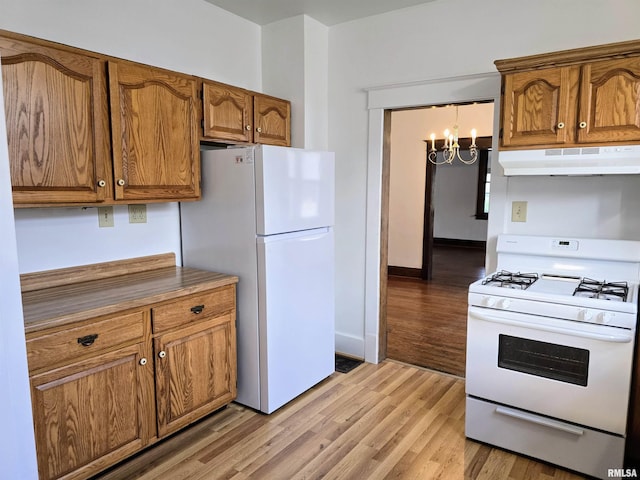 1113 S 5th St, Pekin, IL 61554 - kitchen with under cabinet range hood, white appliances, brown cabinetry, and a chandelier