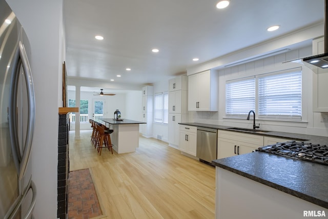 2129 Fondulac Dr, East Peoria, IL 61611 - kitchen with appliances with stainless steel finishes, dark countertops, a kitchen bar, light wood-style floors, and a ceiling fan