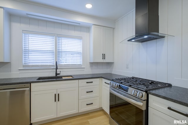 2129 Fondulac Dr, East Peoria, IL 61611 - kitchen featuring appliances with stainless steel finishes, wall chimney exhaust hood, white cabinets, light wood finished floors, and dark stone countertops