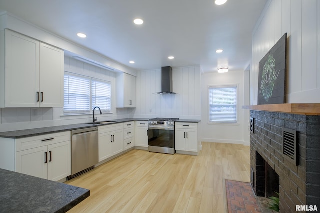 2129 Fondulac Dr, East Peoria, IL 61611 - kitchen featuring stainless steel appliances, wall chimney exhaust hood, dark countertops, a fireplace, and recessed lighting