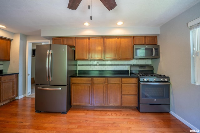 6822 N Kimberly Dr, Peoria, IL 61614 - kitchen featuring appliances with stainless steel finishes, brown cabinetry, dark countertops, light wood finished floors, and recessed lighting