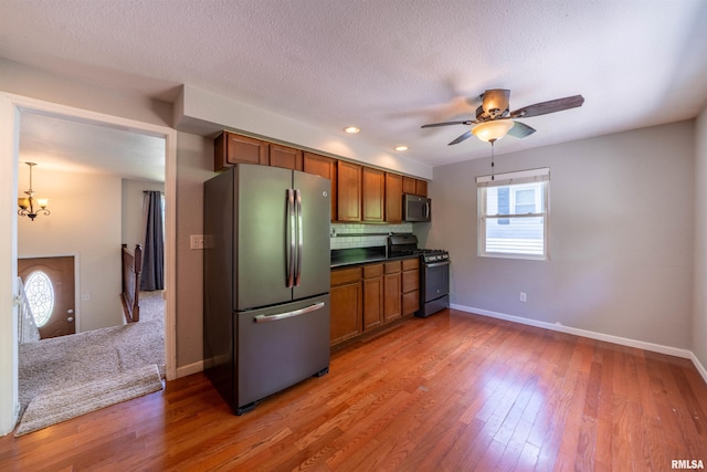 6822 N Kimberly Dr, Peoria, IL 61614 - kitchen with stainless steel appliances, brown cabinetry, light wood finished floors, decorative backsplash, and dark countertops