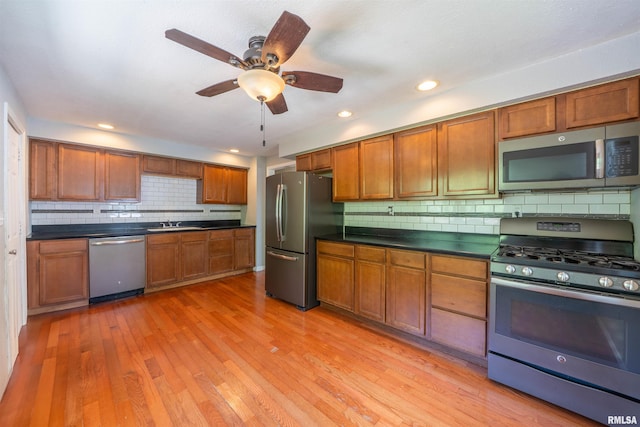 6822 N Kimberly Dr, Peoria, IL 61614 - kitchen featuring stainless steel appliances, backsplash, dark countertops, light wood-style flooring, and brown cabinets