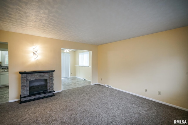 2705 W Millbrook Ct, Peoria, IL 61615 - unfurnished living room featuring carpet flooring, a stone fireplace, a textured ceiling, and ceiling fan