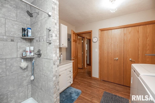 1701 Woodland Knolls Rd, Metamora, IL 61548 - full bathroom featuring separate washer and dryer, vanity, a tile shower, wood finished floors, and a textured ceiling