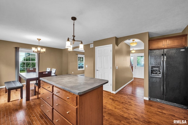 1129 Stonelake Ct, Metamora, IL 61548 - kitchen featuring black fridge with ice dispenser, dark wood finished floors, a kitchen island, brown cabinetry, and pendant lighting