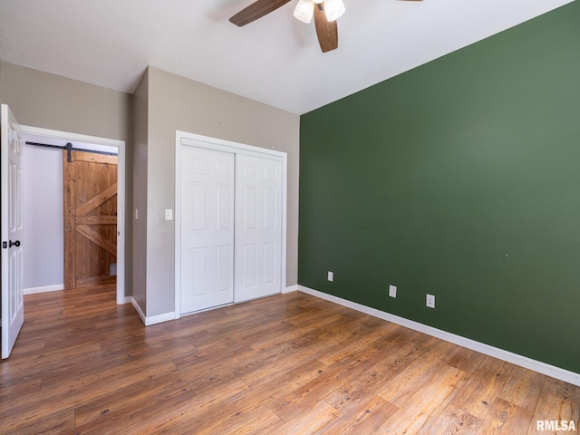 797 State Route 29th Hwy, Sparland, IL 61565 - unfurnished bedroom with a closet, hardwood / wood-style flooring, ceiling fan, and a barn door