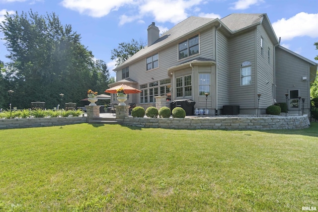 2815 W Windpointe Dr, Peoria, IL 61614 - back of property featuring a chimney, a lawn, and a patio