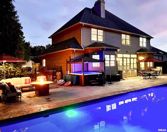 2815 W Windpointe Dr, Peoria, IL 61614 - back of house at dusk featuring a hot tub, a patio, a chimney, an outdoor living space with a fire pit, and a shingled roof