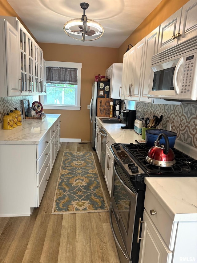 994 N Crafford St, Bushnell, IL 61422 - kitchen featuring appliances with stainless steel finishes, wood finished floors, tasteful backsplash, white cabinetry, and glass insert cabinets