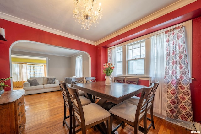 1922 W Rohmann Ave, West Peoria, IL 61604 - dining room with arched walkways, light wood finished floors, ornamental molding, and a chandelier