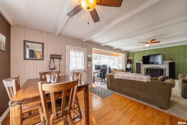 1922 W Rohmann Ave, West Peoria, IL 61604 - dining area with ceiling fan, beam ceiling, wooden walls, light wood-style floors, and a fireplace