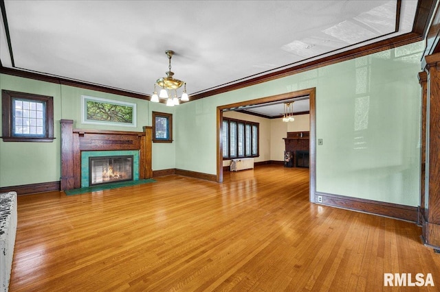 1027 N Maplewood Ave, Peoria, IL 61606 - unfurnished living room with a fireplace with flush hearth, a chandelier, crown molding, light wood-type flooring, and radiator heating unit