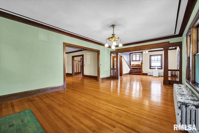 1027 N Maplewood Ave, Peoria, IL 61606 - unfurnished dining area with radiator heating unit, crown molding, stairway, light wood finished floors, and a chandelier