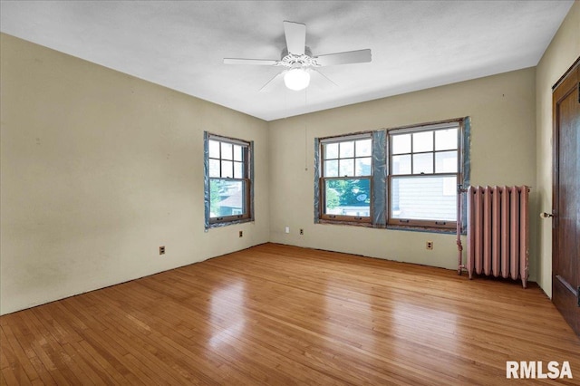 1027 N Maplewood Ave, Peoria, IL 61606 - spare room with radiator heating unit, light wood-style floors, and ceiling fan