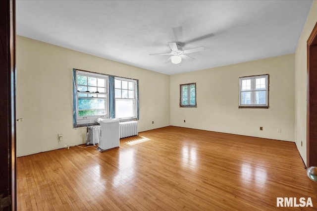 1027 N Maplewood Ave, Peoria, IL 61606 - unfurnished room with radiator, light wood finished floors, and a ceiling fan