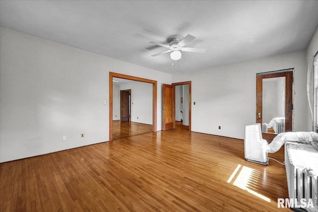 1027 N Maplewood Ave, Peoria, IL 61606 - unfurnished living room featuring radiator, ceiling fan, and wood finished floors