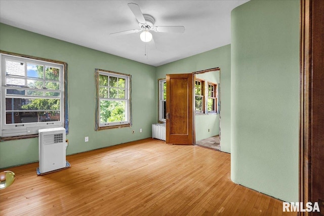 1027 N Maplewood Ave, Peoria, IL 61606 - unfurnished bedroom featuring radiator heating unit, light wood-type flooring, and a ceiling fan