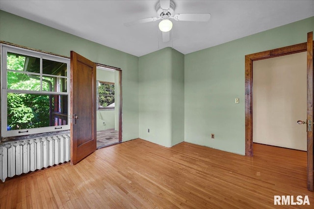 1027 N Maplewood Ave, Peoria, IL 61606 - empty room featuring radiator heating unit, light wood finished floors, and ceiling fan